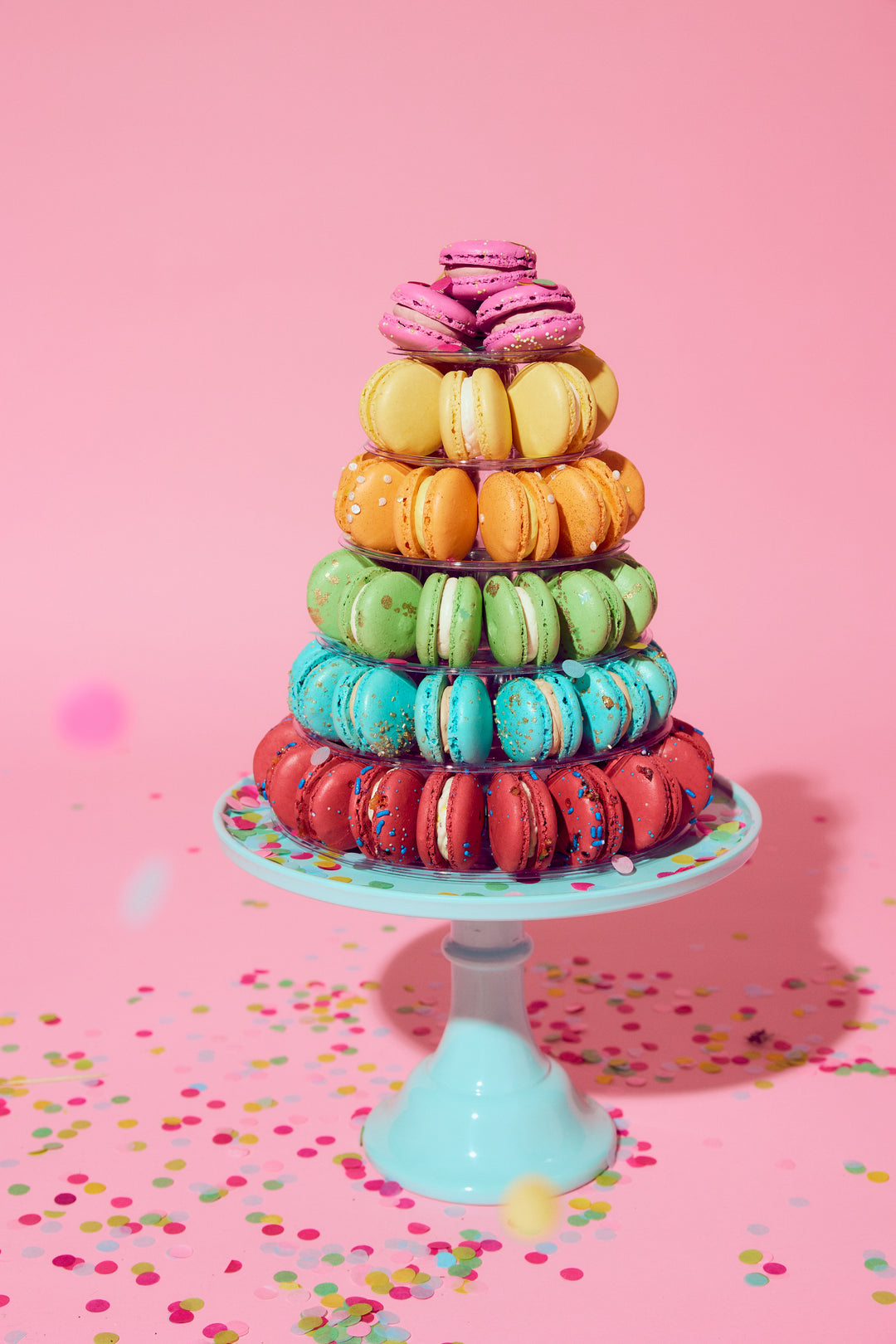 Colorful macaron tower on a pink background with confetti